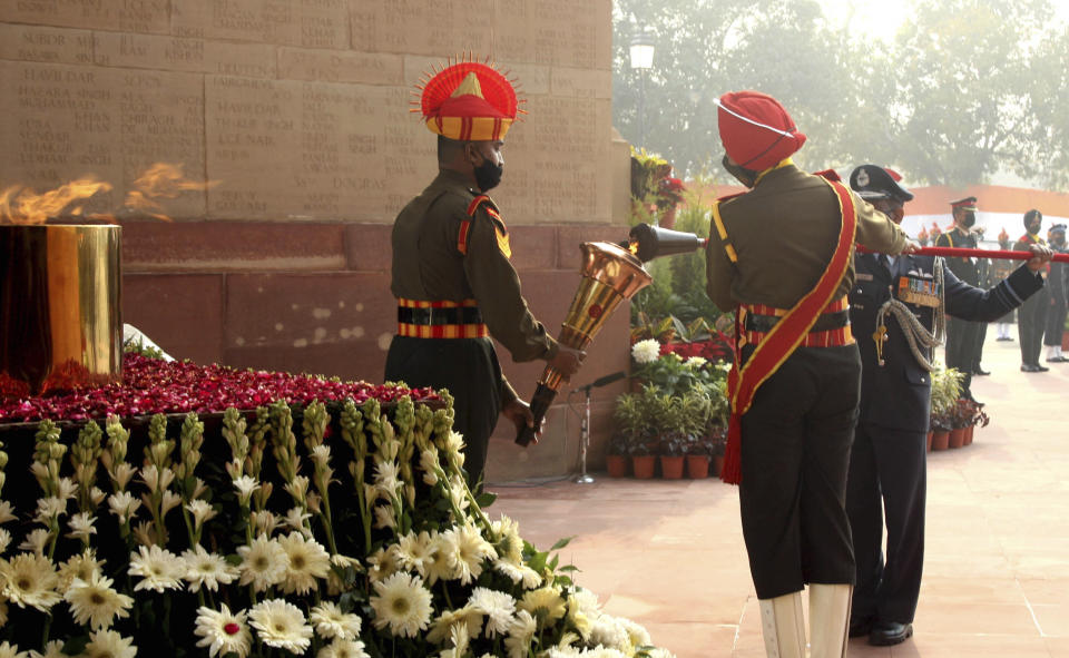 This handout photograph provided by the Indian Army shows a soldier light a torch from the eternal flame for a ceremonious march to the war memorial, less than half a kilometer away, in New Delhi, India, Friday, Jan. 21, 2022. Indian Prime Minister Narendra Modi’s government came under fire from the opposition on Friday for shifting "an eternal flame” honoring Indian soldiers killed in the 1971 war with Pakistan to a new National War Memorial he inaugurated nearly three years ago. Rahul Gandhi, a top Congress party leader, accused the government of “removing history” by extinguishing the flame at the India Gate. The flame was lit by his grandmother and then Prime Minister Indira Gandhi in 1972. (Indian Army via AP)