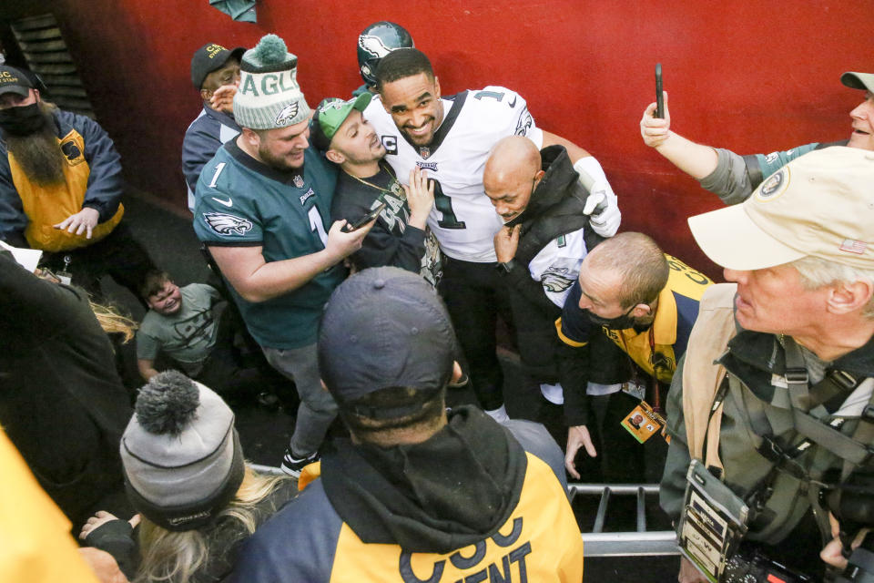 Fans fall on Philadelphia Eagles quarterback Jalen Hurts (1) after beating the Washington Football Team 20-16 on Sunday, January 2, 2022 in Landover, Maryland.(Shaban Athuman/Richmond Times-Dispatch via AP)