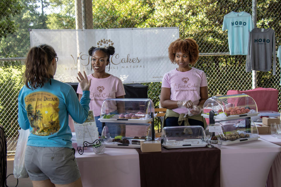 Jasmyn Reddicks, left, owner of VTasteCakes, talks with a customer at the Athens, Ga., Farmer's Market. The new bakery focuses on vegan cupcakes with plans for a line of cakes in development.