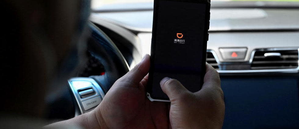 (FILES) This file photo taken on July 2, 2021 shows a driver opening the Didi Chuxing ride-hailing app on his smartphone in Beijing. - Chinese ride-hailing giant Didi Chuxing said on December 3, 2021, it would start the process of de-listing its shares from the New York stock exchange, shortly after US regulators adopted a rule that would allow them to remove foreign firms. (Photo by Jade GAO / AFP)