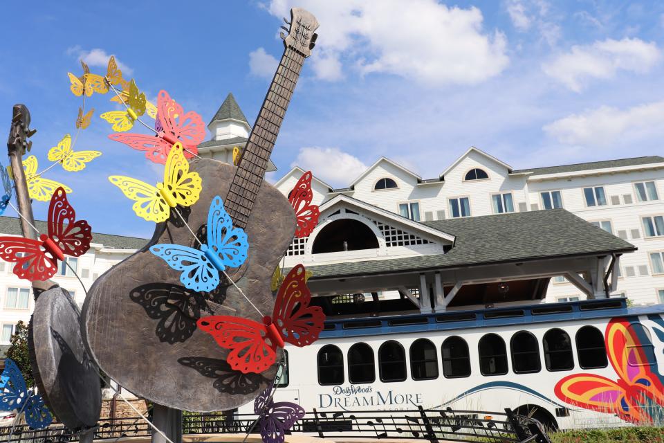 Outside the Dollywood DreamMore Resort. A guitar-shaped statue with butterflies in the foreground, the white hotel building in the background