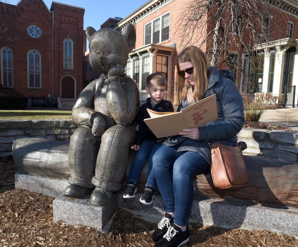 Emily Breitner of South Rockwood reads to her 3-year-old son, Bennett, at the Little Brown Bear statue outside the Dorsch Memorial Library in downtown Monroe.