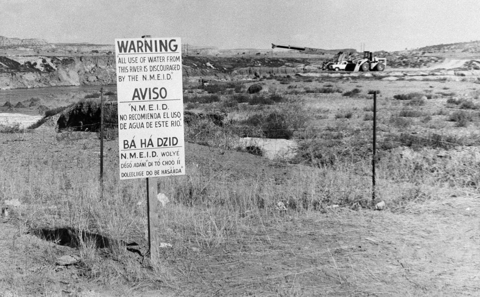 FILE - In this Nov. 13, 1979, file photo, while United Nuclear Corp. uses a combination of hand work and heavy machinery to clear up a uranium tailings spill along the Rio Puerco, signs warn residents in three languages to avoid the water in Church Rock, N.M. A bipartisan group of lawmakers is renewing the push to expand a federal compensation program for radiation exposure following uranium mining and nuclear testing carried out during the Cold War. Advocates have been trying for years to bring awareness to the lingering effects of nuclear fallout surrounding the Trinity Site in southern New Mexico and on the Navajo Nation, where more than 30 million tons of ore were extracted over decades to support U.S. nuclear activities. (AP Photo/SMH, File)