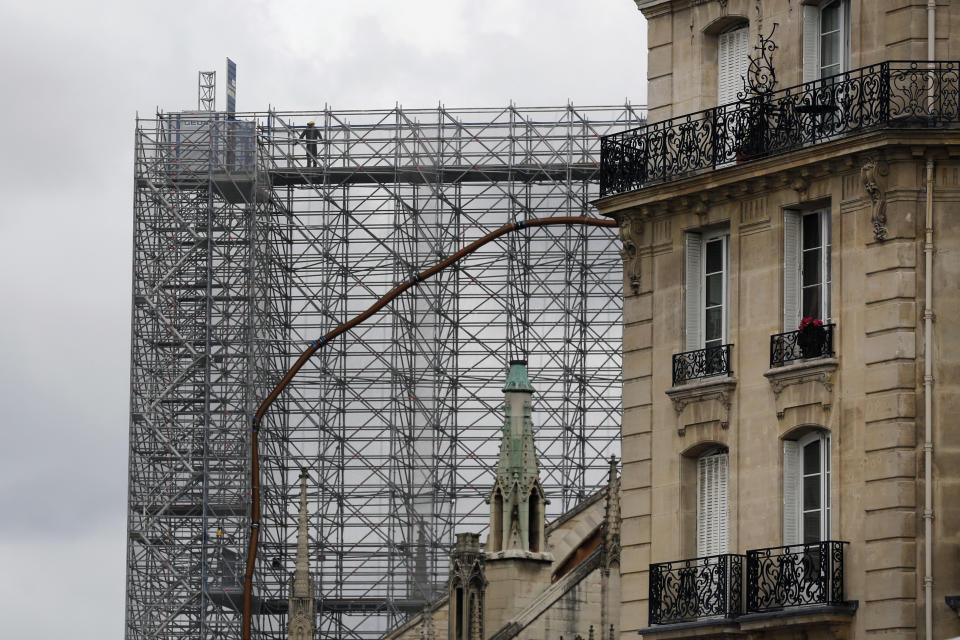 A worker stands on a scaffolding at Notre Dame cathedral, Friday, July 10, 2020 in Paris. Notre Dame Cathedral will be rebuilt just the way it stood before last year's devastating fire. (AP Photo/Thibault Camus)