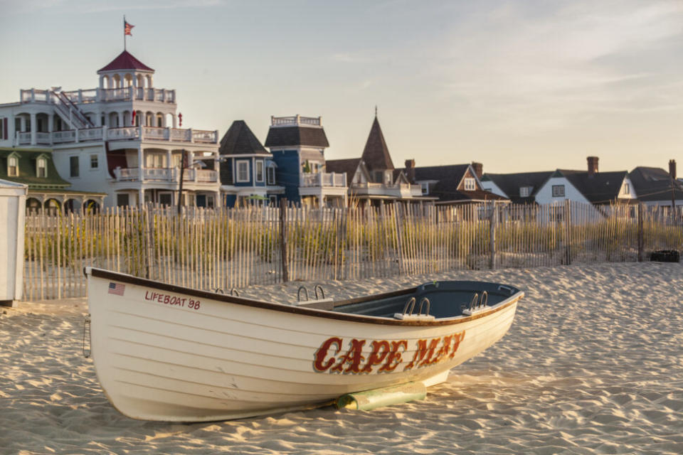 Victorian Homes and hotels line Beach Ave. in Cape May with lifesaving rescue boat on the beach.