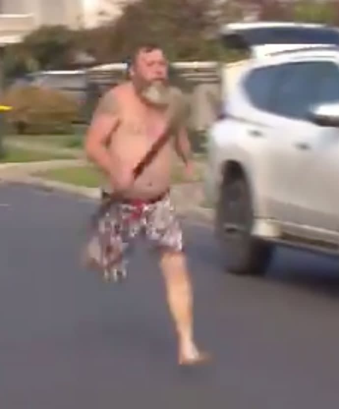 Mr Albrook pictured shirtless and wielding a didgeridoo while running down the street.
