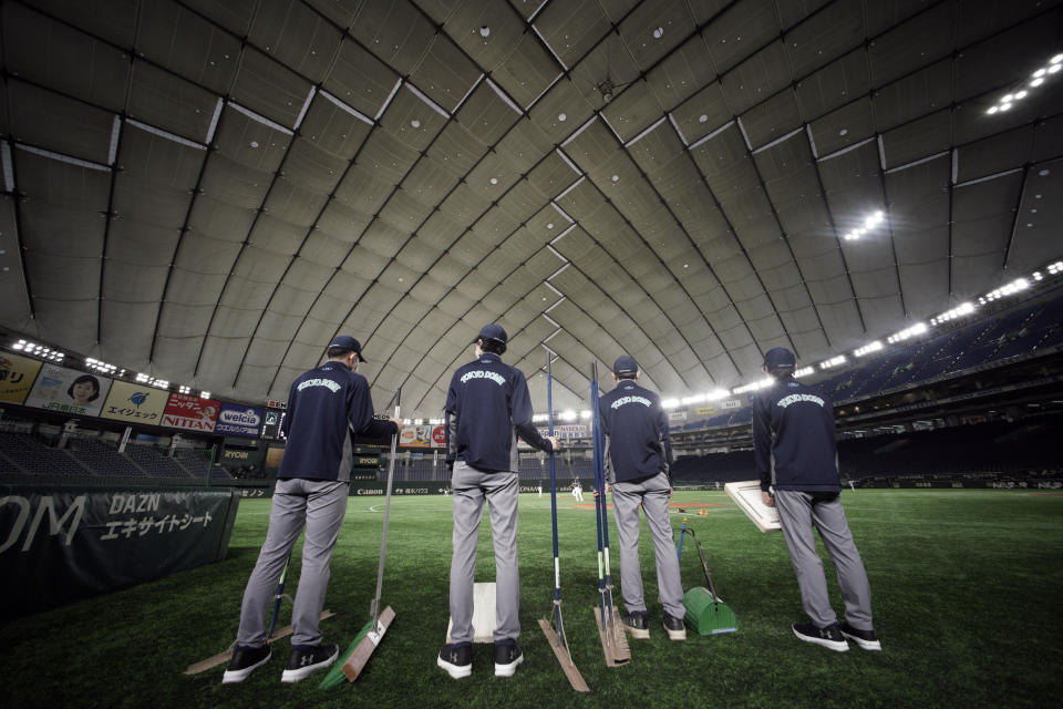 Staffs stand where spectators' stands are empty prior to a preseason baseball game between the Yomiuri Giants and the Yakult Swallows at Tokyo Dome in Tokyo Saturday, Feb. 29, 2020. Japan's professional baseball league said Thursday it will play its 72 remaining preseason games in empty stadiums because of the threat of the spreading coronavirus.(AP Photo/Eugene Hoshiko)