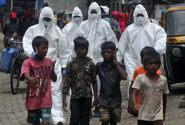 Health workers wearing protective clothing arrive to screen people for Covid-19 symptoms at a slum in Mumbai, India 