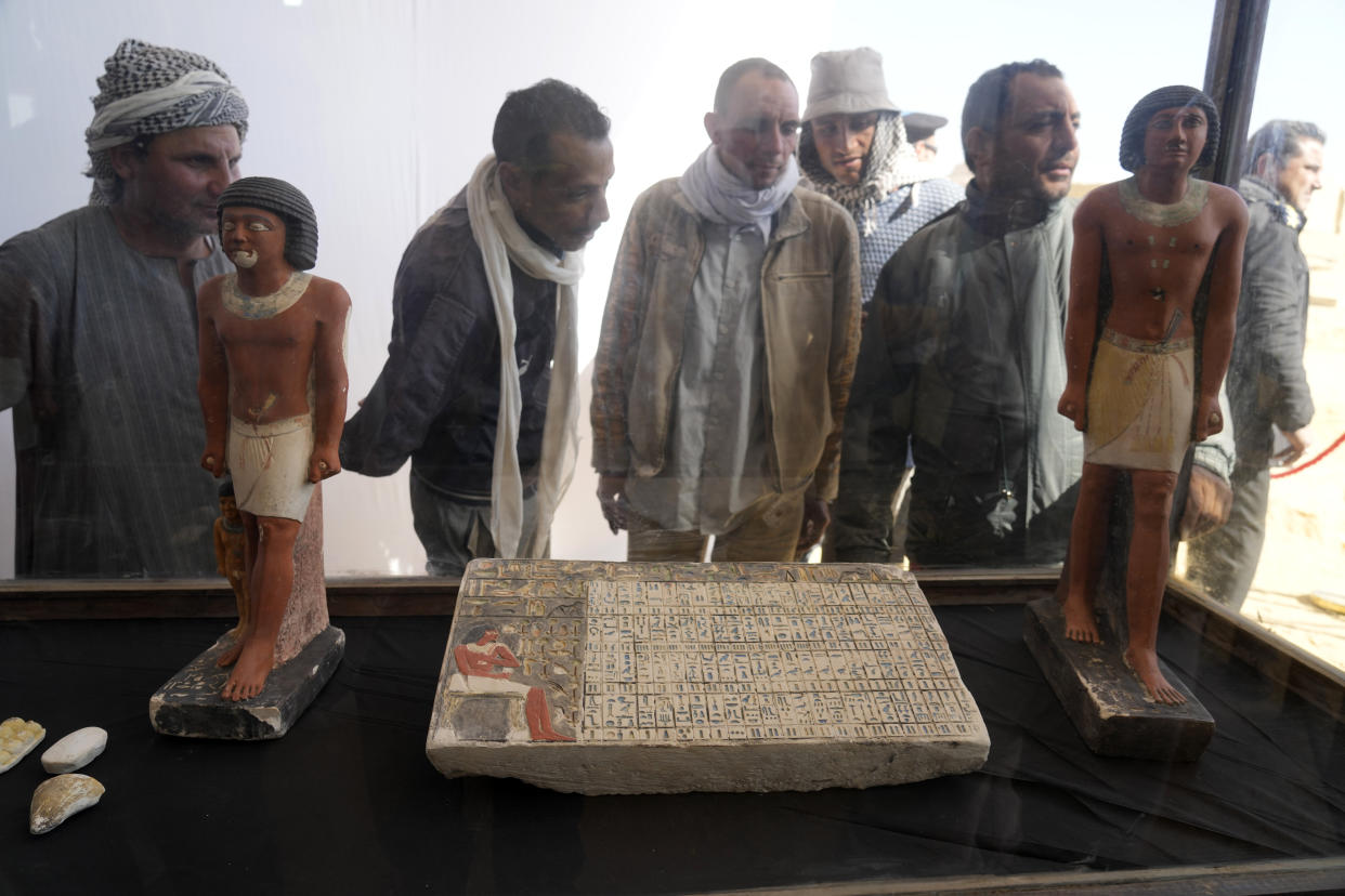 Egyptian antiquities workers watch recently discovered artifacts at the site of the Step Pyramid of Djoser in Saqqara, 24 kilometers (15 miles) southwest of Cairo, Egypt, Thursday, Jan. 26, 2023. Egyptian archaeologist Zahi Hawass, the director of the Egyptian excavation team, announced that the expedition found a group of Old Kingdom tombs dating to the fifth and sixth dynasties of the Old Kingdom, indicating that the site comprised a large cemetery. (AP Photo/Amr Nabil)