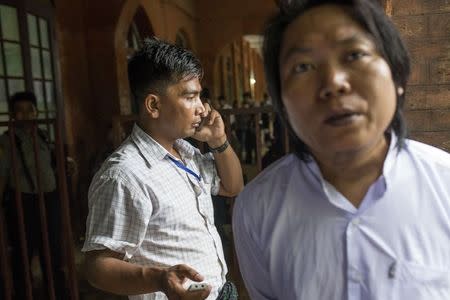 A man who identified himself to Reuters as a plainclothed Special Branch police officer records as student activist Nanda Sit Aung talks to Reuters during an interview at Tharrawaddy court, while on a lunch break at a mass trial of student protesters, Tharrawaddy, Bago, August 25, 2015. REUTERS/Minzayar