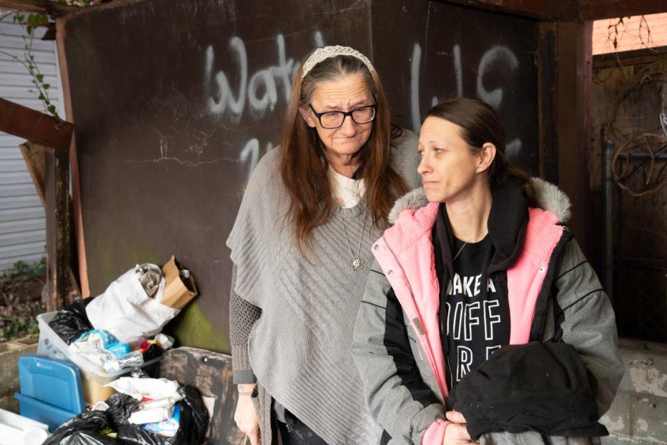 Judi Yates, left, and Jenn Carlson comfort each other outside a burned garage shed in Belleville where Yates’ son, Trent Tuttle, was found dead on Jan. 19. Carlson is a longtime family friend.