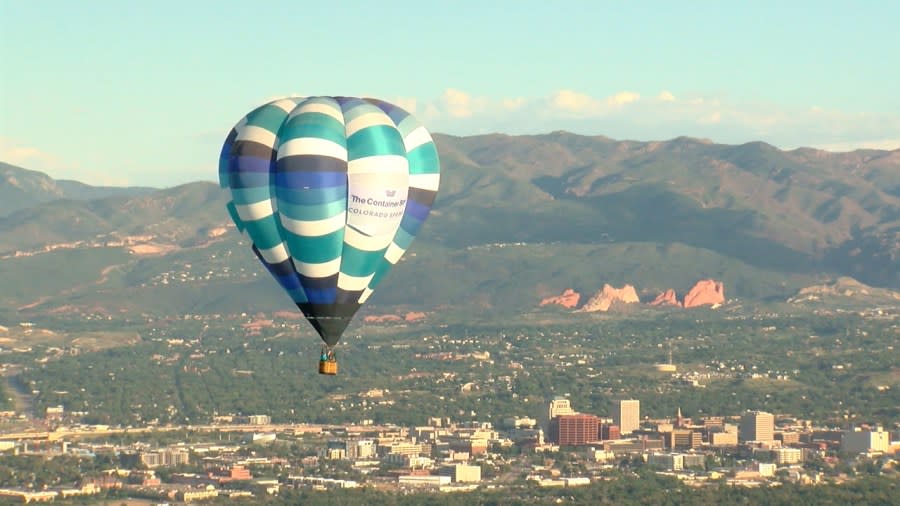 A hot air balloon sails the skies over Colorado Springs with downtown in the background