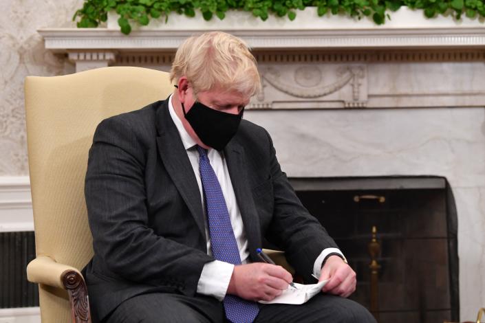 Britain&#39;s Prime Minister Boris Johnson writes down notes as he holds a bilateral meeting with US President Joe Biden (out of frame) at the Oval Office of the White House in Washington, DC on September 21, 2021. (Photo by Nicholas Kamm / AFP) (Photo by NICHOLAS KAMM/AFP via Getty Images)