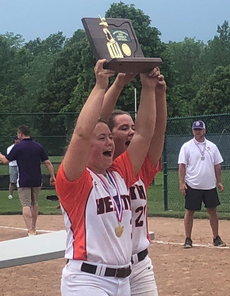 Heath seniors Katlyn Jardine and Makayla Jardine raise the Division II district championship trophy following the Bulldogs' 5-0 victory against Bloom-Carroll at Pickerington Central on Saturday, May 21, 2022.