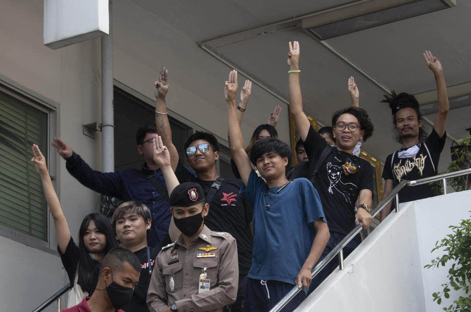 Some of 15 activists and Jatupat Boonpattararaksa, wearing sunglasses at center, raise a three-finger salute, a symbol of resistance, as they turn up at Samranrat police station in Bangkok, Thailand, Friday, Aug, 28, 2020. Anti-government protesters tussled with police on Friday as 15 of their movement leaders turned up at a police station to answer a summons linked to demonstrations denouncing the arrests. (AP Photo/Sakchai Lalit)