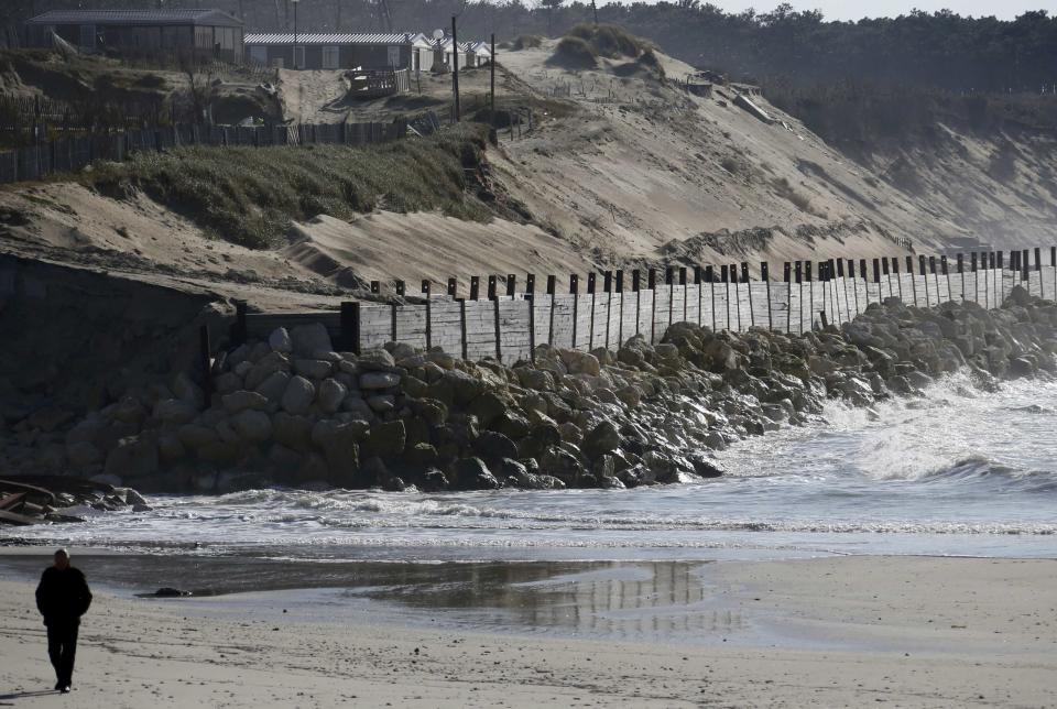 Un hombre camina por la playa junto a los diques instalados en Soulac.