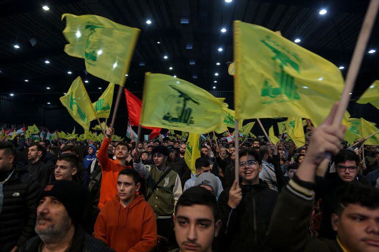 Partidarios proiraníes de Hezbollah asisten a una misa mientras el secretario general de Hezbollah, Hassan Nasrallah, parece dar un discurso televisado para conmemorar el cuarto aniversario del asesinato de Abu Mahdi al-Mohandes, el jefe adjunto del Hashd iraquí la milicia al-Shaabi y el comandante de la Fuerza Quds iraní, Qasem Soleiman, por un dron estadounidense en Irak en 2020.