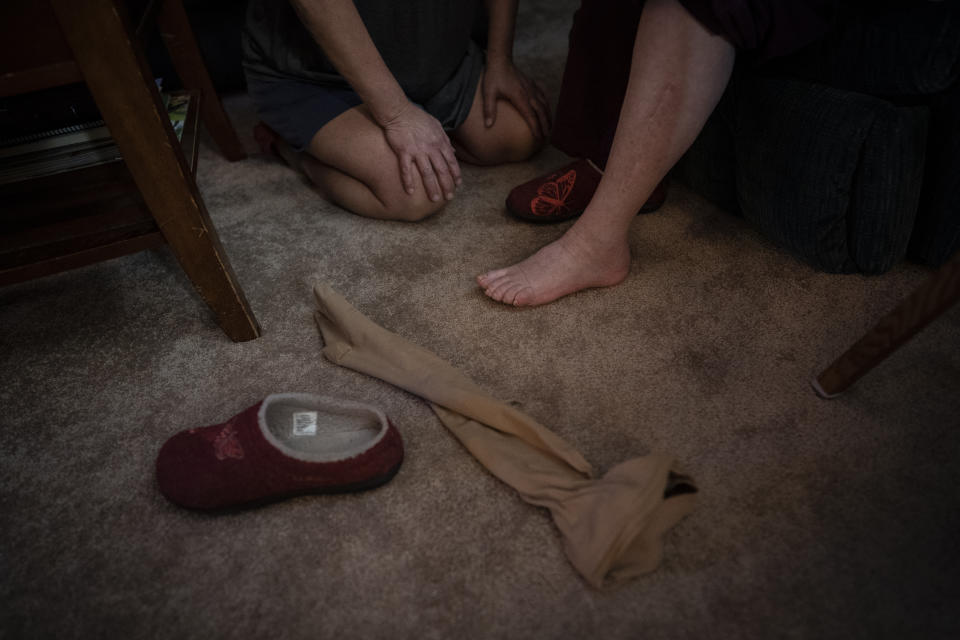 Susan Ryder pauses to catch her breath after struggling with her mother, Betty Bednarowski, to remove compression stockings at the end of the day, Monday, Nov. 29, 2021, in Rotterdam Junction, N.Y. (AP Photo/Wong Maye-E)