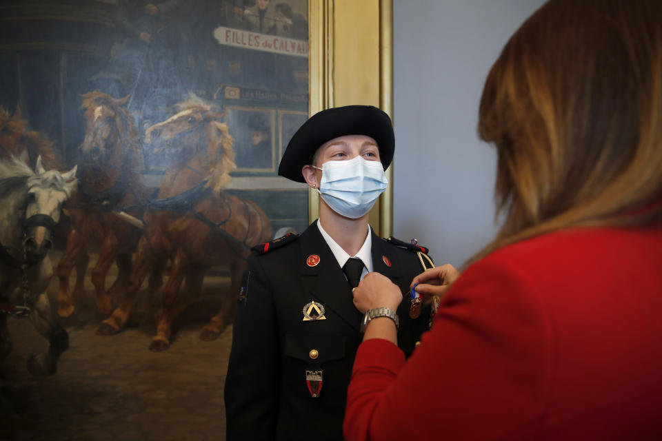 France's minister for citizenship issues, Marlene Schiappa, right, gives a bronze medal for courage and dedication to a math teacher-volunteer fighter, Marion Dehecq as she used CPR to save the life of a jogger, during a ceremony at the Paris fire service headquarters in Paris, France, Monday, May 10, 2021. The jogger's wife, Paris-based Associated Press journalist Lori Hinnant, helped identify the anonymous rescuer by putting up thank-you signs in Monceau Park, where her husband Peter Sigal went into cardiac arrest on April 28. (AP Photo/Francois Mori, pool)