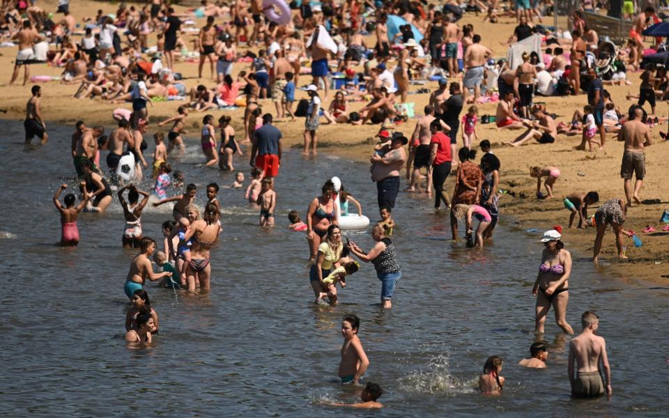 People enjoy the sunshine on a beach at Ruislip Lido near London on Sunday, the day before the restrictions were officially eased - Shutterstock 