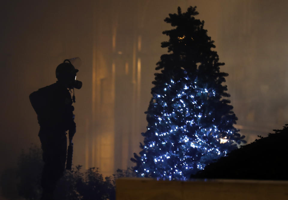 A riot police officer stands next of a Christmas tree during a protest where some anti-government protesters try to enter parliament square in downtown Beirut, Lebanon, Saturday, Dec. 14, 2019. The recent clashes marked some of the worst in the capital since demonstrations began two months ago. The rise in tensions comes as politicians have failed to agree on forming a new government. (AP Photo/Hussein Malla)