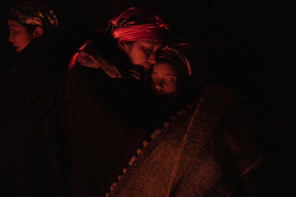 Nicole Yasmin Rojas embraces her 9-year-old daughter, Amy, during a celebration of We Tripantu, the Mapuche new year, inside a ruka, or traditional thatch-roofed rural dwelling, in Carimallin, southern Chile, on Sunday, June 26, 2022. (AP Photo/Rodrigo Abd)