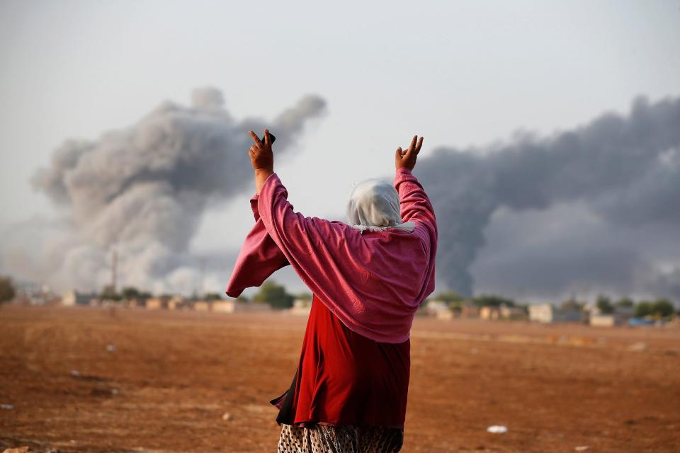 Kiymet Ergun, a Syrian Kurd, gestures as she watches from Mursitpinar, Turkey,  as allied aircraft attack Islamic State targets on Oct. 13 in Kobani, Syria.