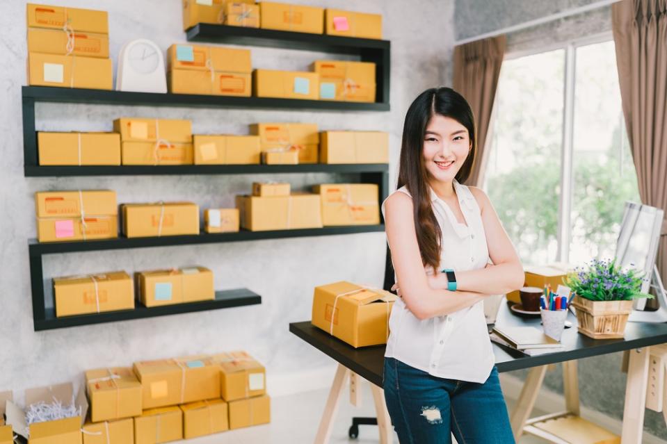 Asian woman with boxes ready for shipping behind her.