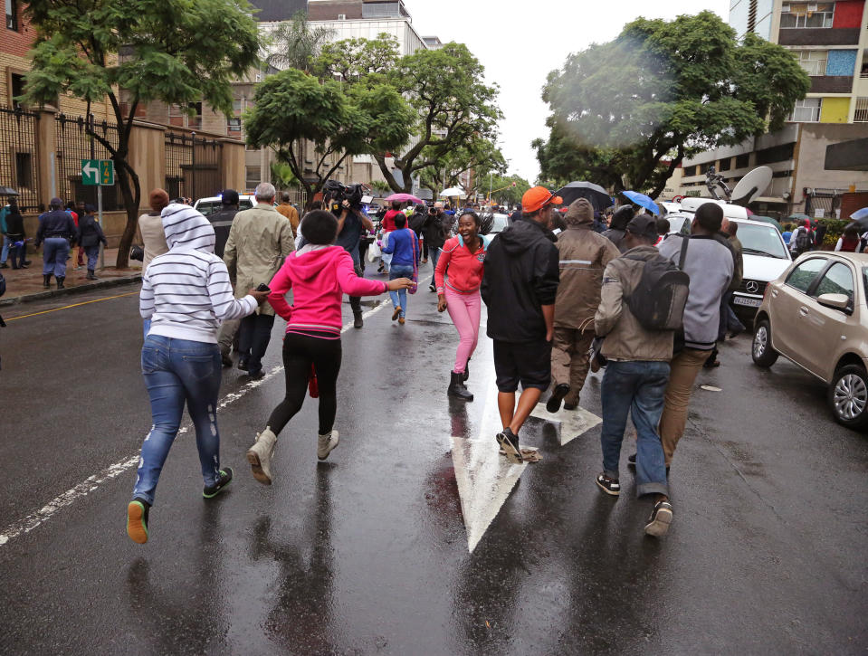 People run after the car that is transporting Oscar Pistorius from the high court after the first day of his trial in Pretoria, South Africa, Monday, March 3, 2014. Pistorius is charged with murder with premeditation in the shooting death of girlfriend Reeva Steenkamp in the pre-dawn hours of Valentine's Day 2013. (AP Photo/Schalk van Zuydam)