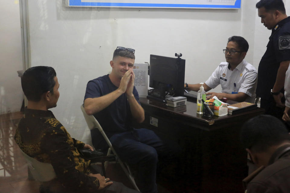 Bodhi Mani Risby-Jones from Queensland, Australia, center, gestures at photographers after his arrival at the local immigration office in Meulaboh, Aceh, Indonesia on Wednesday, June 7, 2023. The Australian surfer who was jailed for attacking several people while drunk and naked in Indonesia's deeply conservative Muslim province of Aceh will be deported back to his country after he agreed to apologize and pay compensation, officials said Wednesday. (AP Photo/Sultan Ikbal Abiyyu)