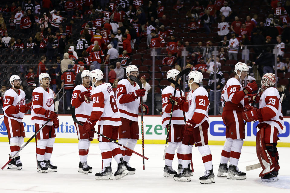 Detroit Red Wings goaltender Alex Nedeljkovic (39) is congratulated by teammates after the third period of an NHL hockey game against the New Jersey Devils Saturday, Oct. 15, 2022, in Newark, N.J. The Red Wings won 5-2. (AP Photo/Adam Hunger)