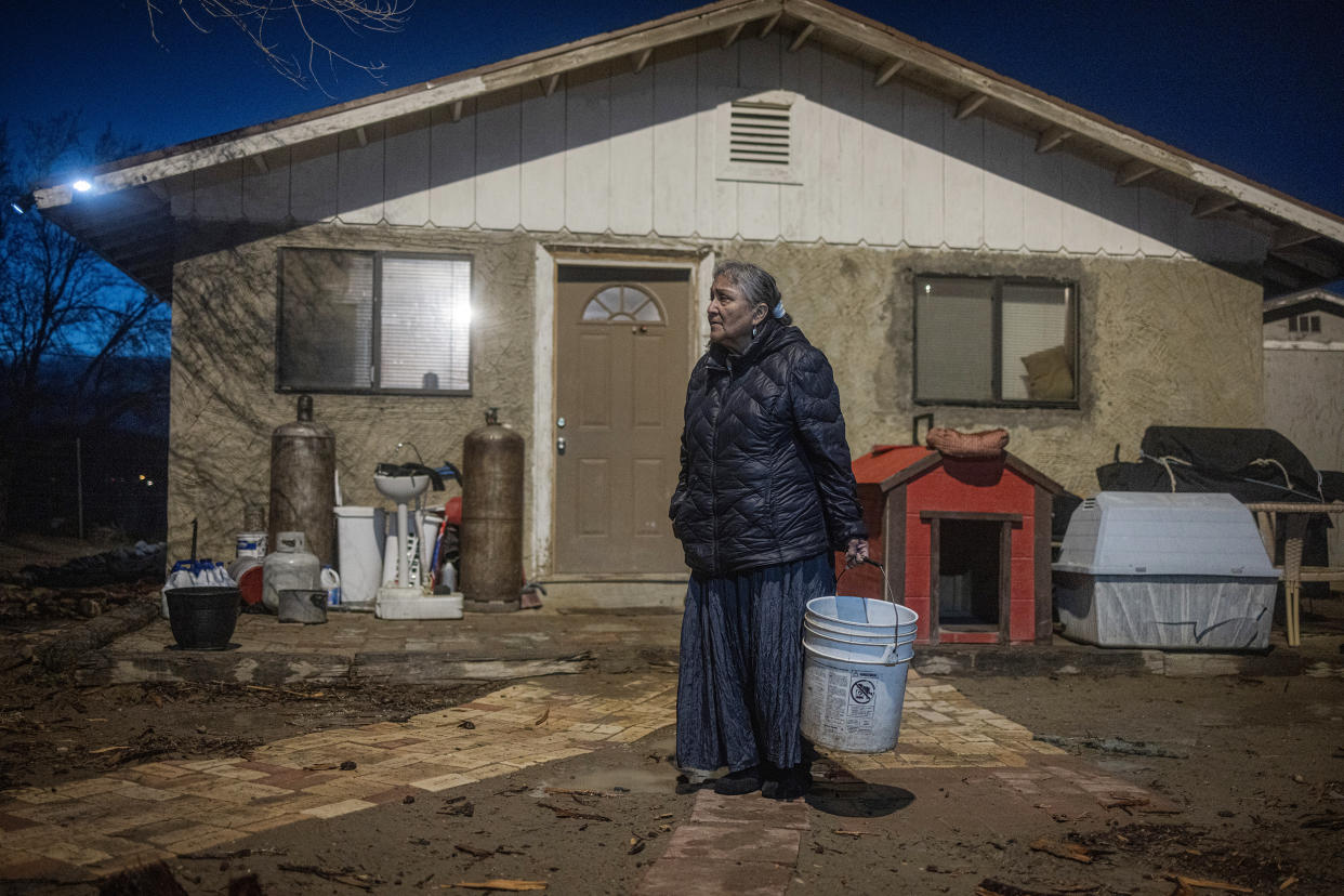 Marilyn Help-Hood,66, holds a bucket to pour her dirty water into on March 13, 2023. (Sharon Chischilly for NBC News)