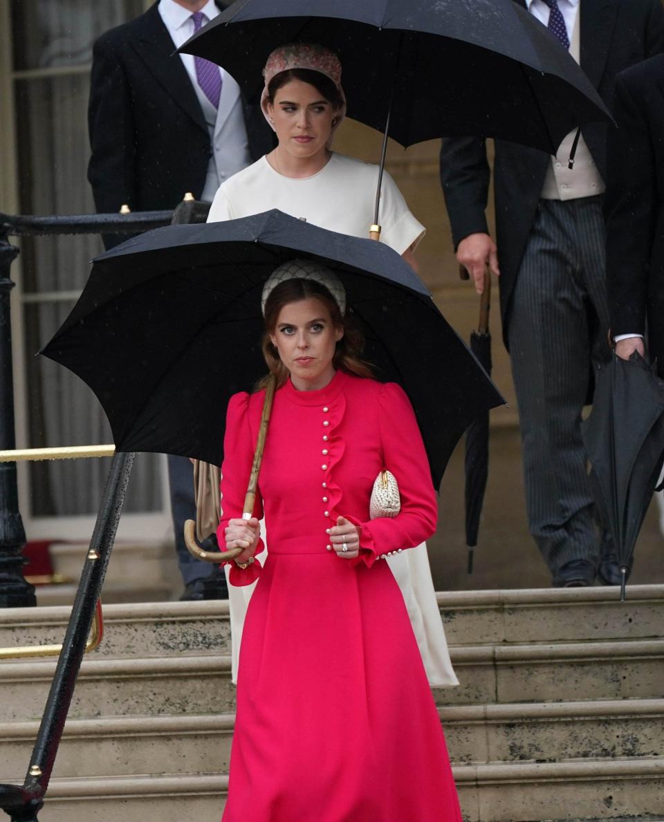 Princesses Beatrice and Eugenie shielded from the rain as they arrived at the party