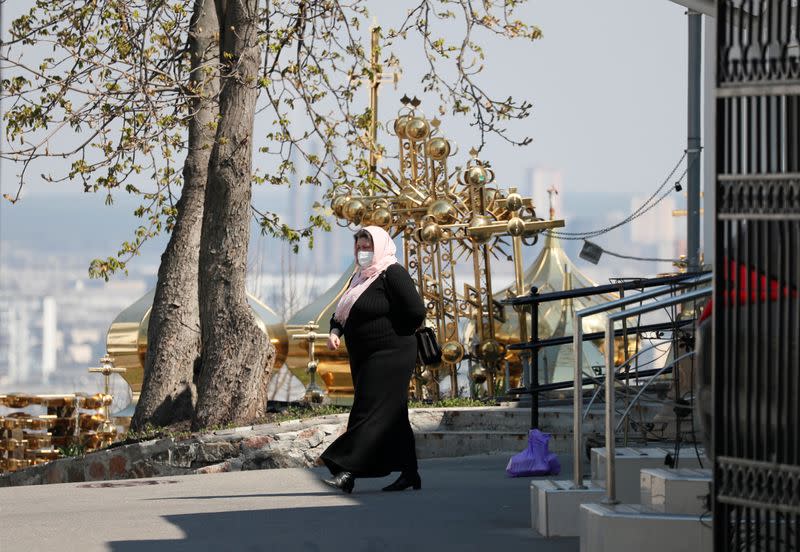 A woman wearing a protective face mask walks in the territory of the Kiev Pechersk Lavra monastery in Kiev