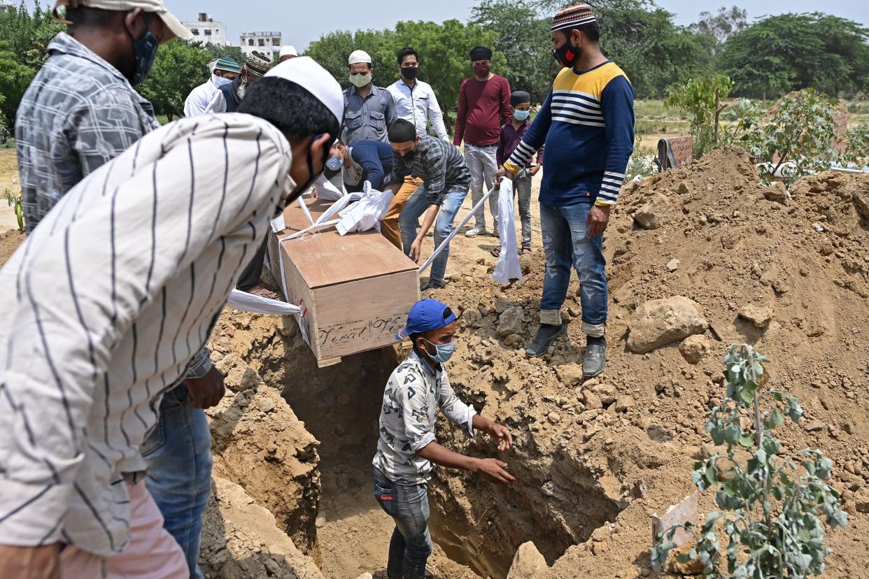 Relatives, friends and graveyard workers prepare to lower the body of a Covid-19 coronavirus victim during the burial at a graveyard in New Delhi on April 28, 2021.