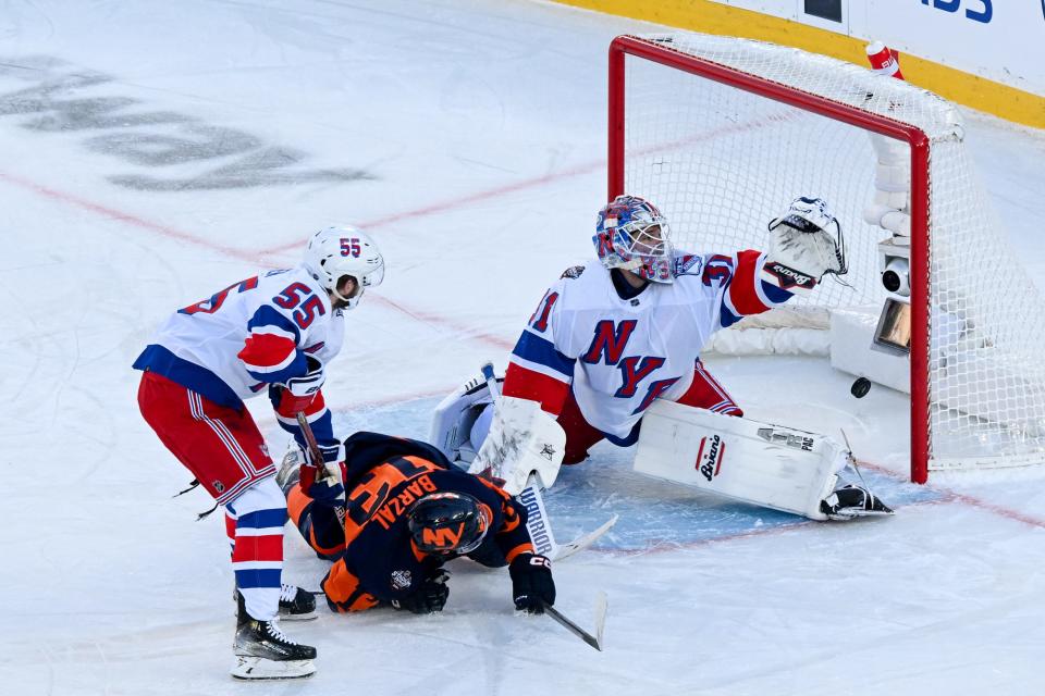Feb 18, 2024; East Rutherford, New Jersey, USA; New York Islanders center Mathew Barzal (13) scores a goal past New York Rangers goaltender Igor Shesterkin (31) defended by New York Rangers defenseman Ryan Lindgren (55) during the first period in a Stadium Series ice hockey game at MetLife Stadium. Mandatory Credit: Dennis Schneidler-USA TODAY Sports