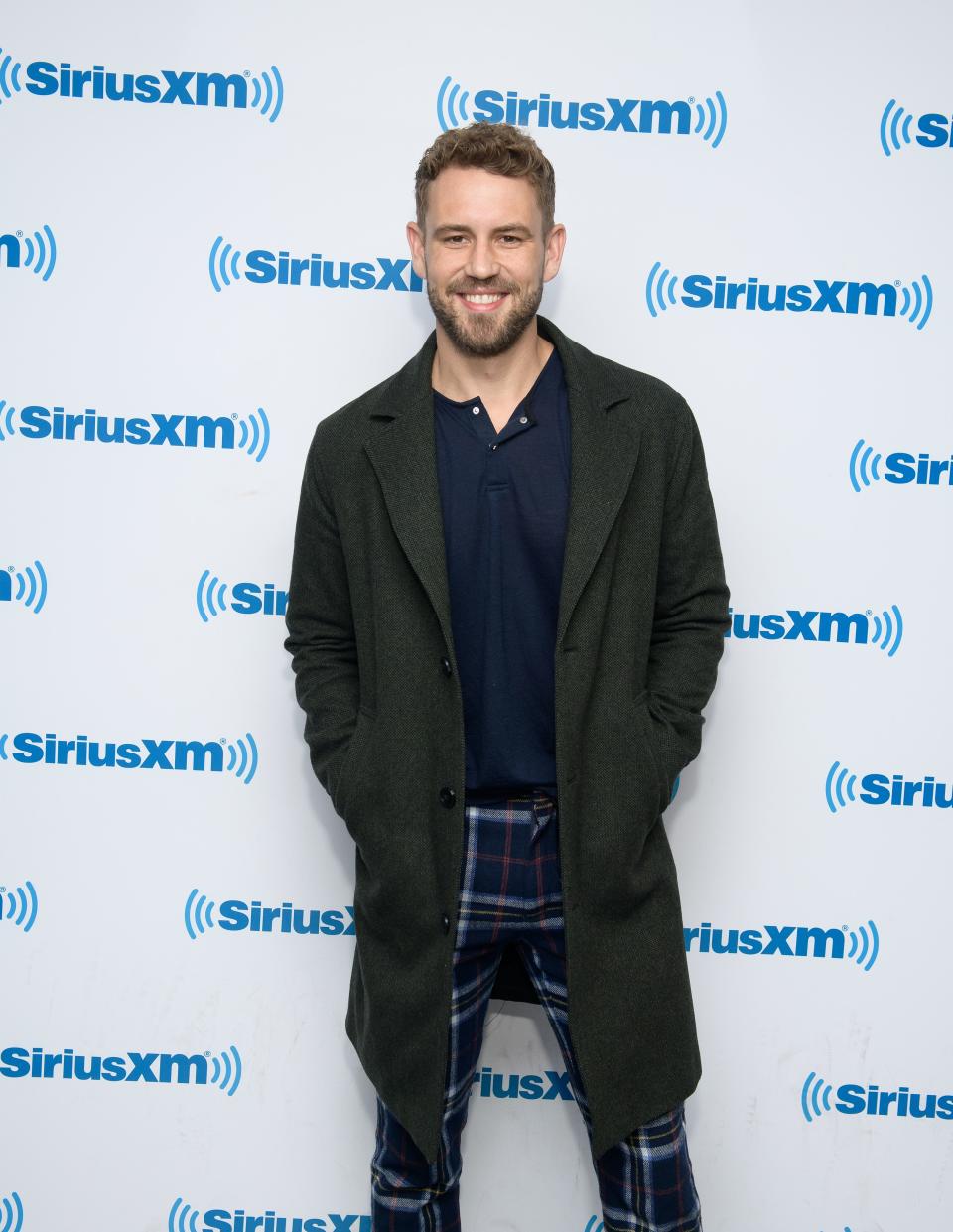 Nick Viall looks fashionable in blue pant and T-shirt, with a black coat, and the smile on his face is beautiful