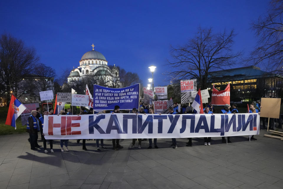 People hold a banner reading: "No to capitulation" as they march during a protest against the Serbian authorities and French-German plan for the resolution of Kosovo in Belgrade, Serbia, Friday, March 17, 2023. Friday marks the 19th anniversary of an attack on minority Serbs by Kosovo extremists that sent thousands fleeing their homes. (AP Photo/Darko Vojinovic)