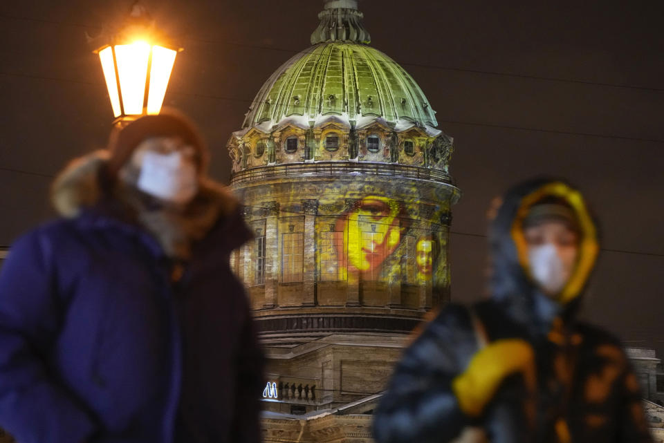 People walk past the Kazansky Cathedral with a projected Orthodox icon Virgin of Kazan during the Orthodox Christmas in St. Petersburg, Russia, Friday, Jan. 7, 2022. Russian Orthodox believers celebrate Christmas in accordance to the Julian calendar on Jan. 7. (AP Photo/Dmitri Lovetsky)