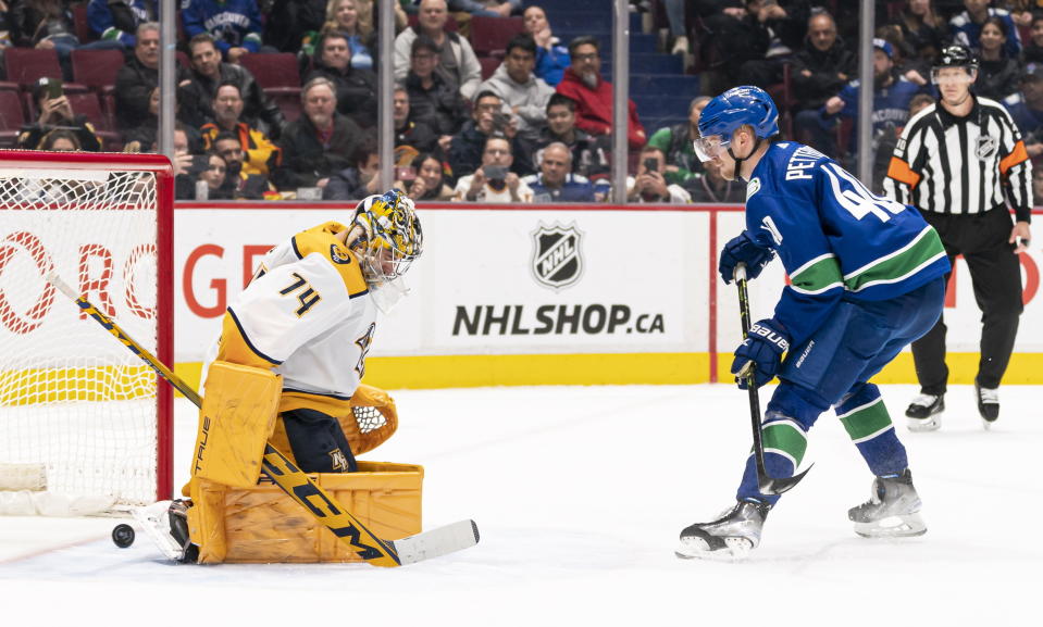 Vancouver Canucks' Elias Pettersson, right, scores on Nashville Predators goalie Juuse Saros during the shootout in an NHL hockey game in Vancouver, British Columbia, Monday, March 6, 2023. The Canucks defeated the Predators 4-3. (Rich Lam/The Canadian Press via AP)
