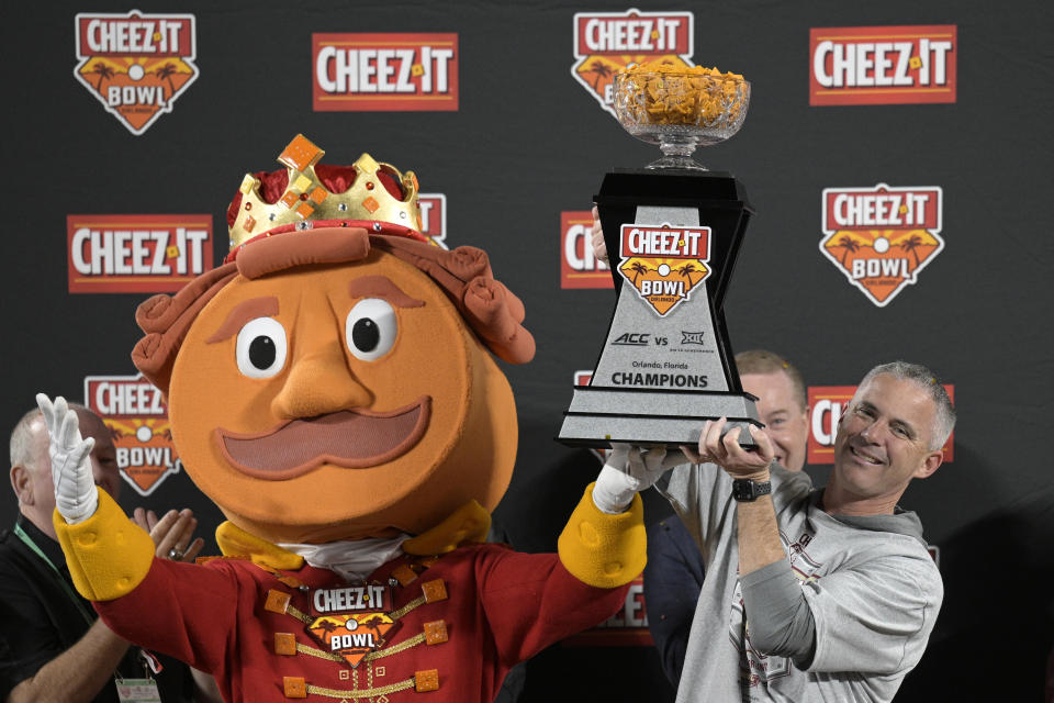 Florida State coach Mike Norvell, right, raises the trophy after the team's win against Oklahoma during the Cheez-It Bowl NCAA college football game Thursday, Dec. 29, 2022, in Orlando, Fla. (AP Photo/Phelan M. Ebenhack)