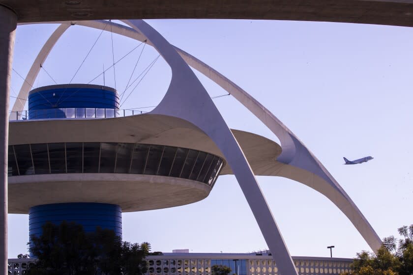 Los Angeles, CA - November 23: An airplane lifts off as viewed with the Theme Building in the foreground as travelers navigate a busy Los Angeles International Airport amid the Thanksgiving holiday rush in Los Angeles on Tuesday, Nov. 23, 2021. (Allen J. Schaben / Los Angeles Times)