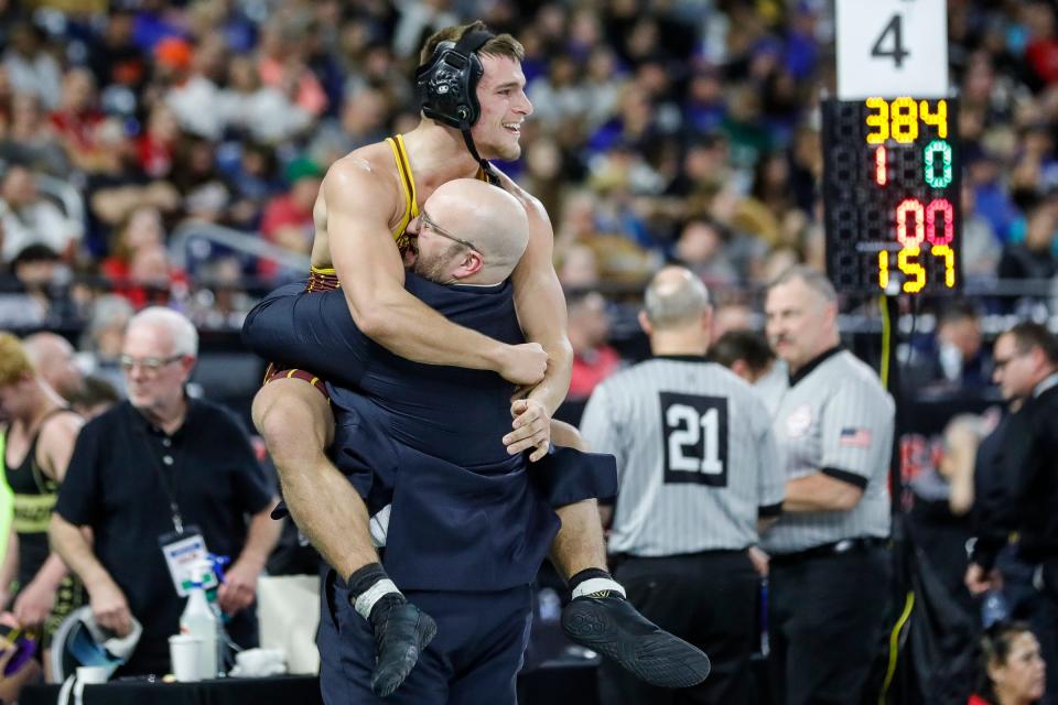 Gavin Schoff of Brandywine hugs his coach to celebrate winning the Division 4 157 pounds match at MHSAA individual wrestling state finals at Ford Field in Detroit on Saturday, March 2, 2024.