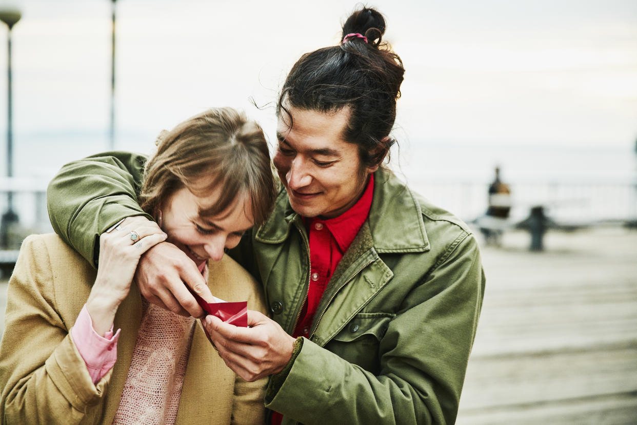 Laughing couple embracing and sharing chocolate while on date