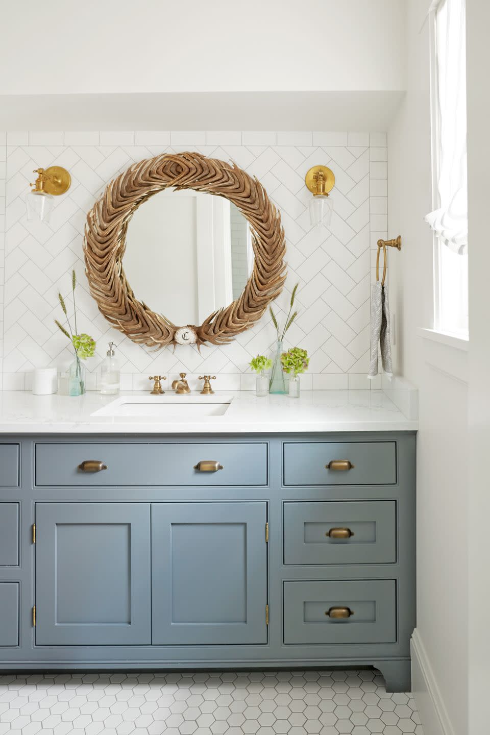 bathroom with gray blue vanity and round mirror made of shed antlers