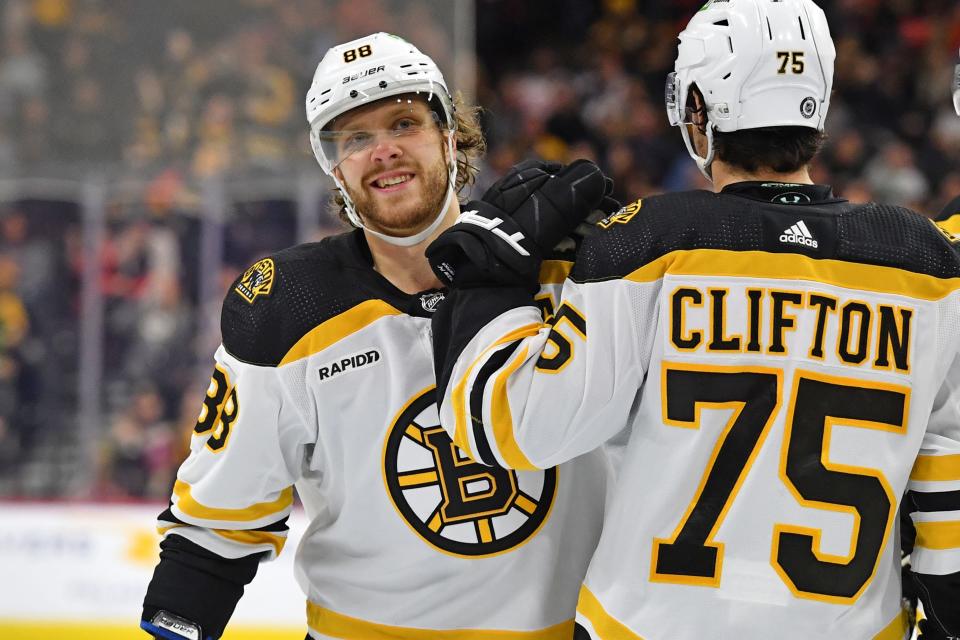 Křídelník Boston Bruins David Pasternak vlevo slaví svůj gól s krajním obráncem Connorem Cliftonem.  Pastrňák v neděli vstřelil hattrick a dosáhl šedesátky za sezónu.