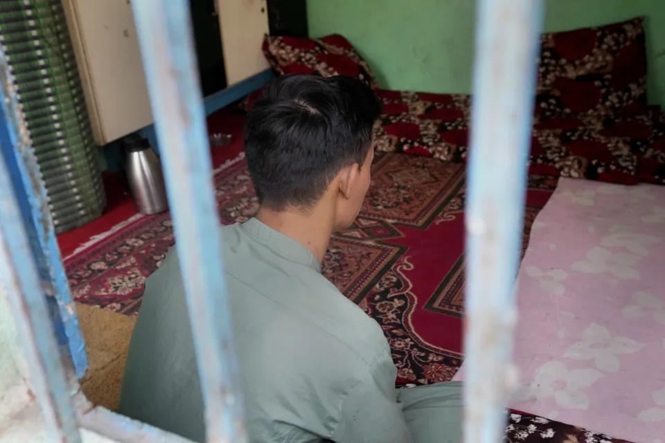 An 18-year-old Afghan boy, who asked not to use his name and not to show his face fearing his identity could lead to his capture again, pose for photograph behind a window during an interview with The Associated Press, in Karachi, Pakistan, Friday, Jan. 26, 2024. Born and raised in Pakistan to parents who fled neighboring Afghanistan half a century ago, an 18-year-old found himself at the mercy of police in Karachi who took his cash, phone and motorbike, and sent him to a deportation center. (AP Photo/Fareed Khan)