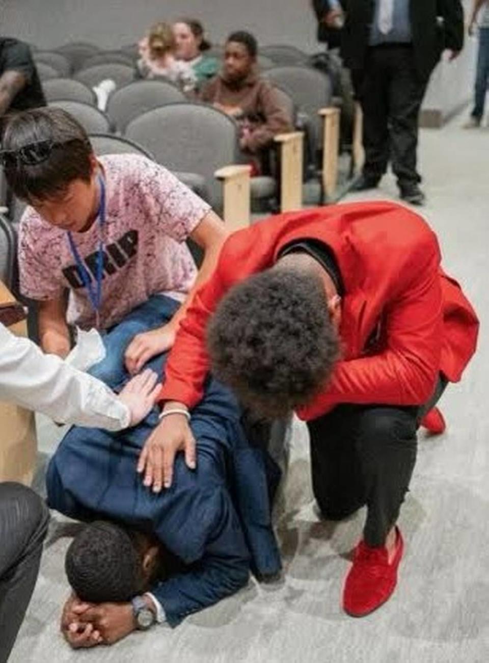 Emoni Shears, right, kneels for a prayer during a church service.