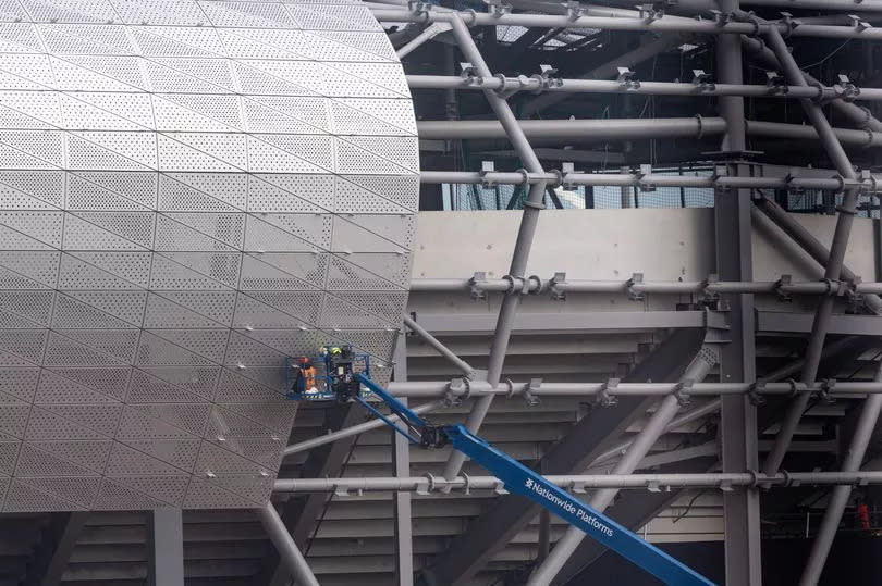 Construction workers apply the exterior cladding to Everton's new stadium