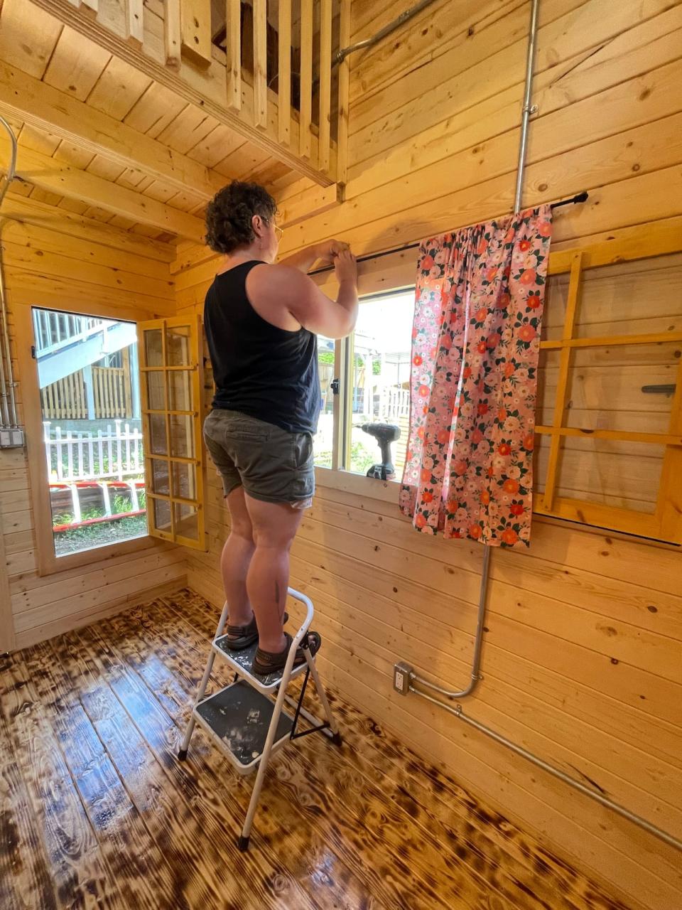 Brett Mason, seen here hanging curtains on the cabin being rented out as an Airbnb, said that finding affordable rentals in B.C. is extremely hard.